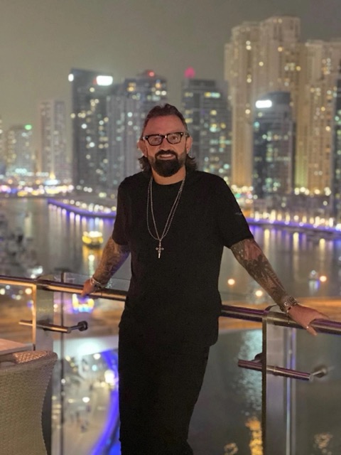 Terry Fisher on a balcony above a lit marina at night