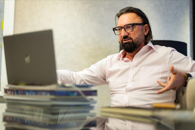 Terry Fisher in a pink shirt making a point across a desk