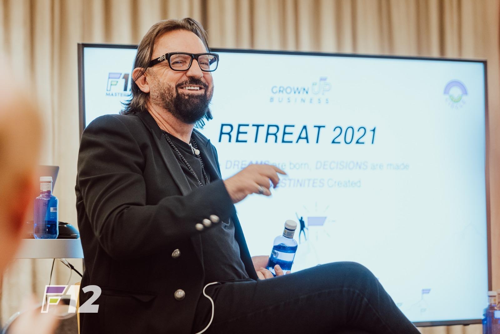 Terry Fisher smiling and gesturing on stage in front of a Retreat 2021 presentation screen